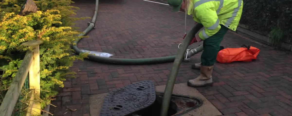 Septic tank cleaning technician servicing a septic tank with a vacuum hose in Mansfield, MA