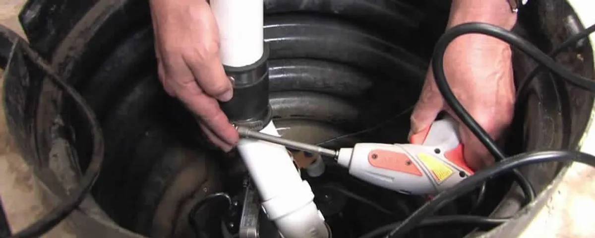 Sump pump installation technician connecting PVC discharge piping in Mansfield, MA